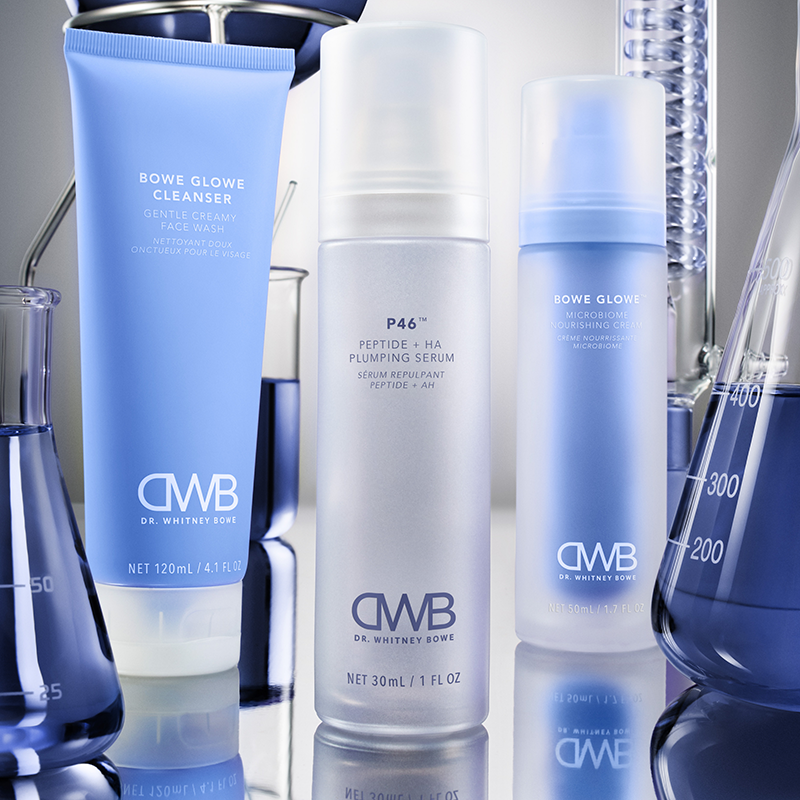 Set of DWB skincare products including a bowe glowe cleanser, p46, and bowe glowe microbiome nourishing cream with DWB branding on a reflective surface